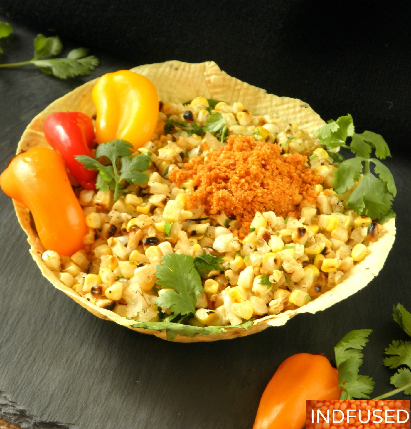 India's favorite street corn served hurda style with red chutney in an edible papad bowl!